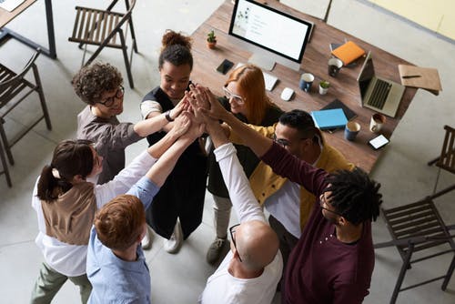 Group of people standing in a circle with arms raised and touching hands in the middle